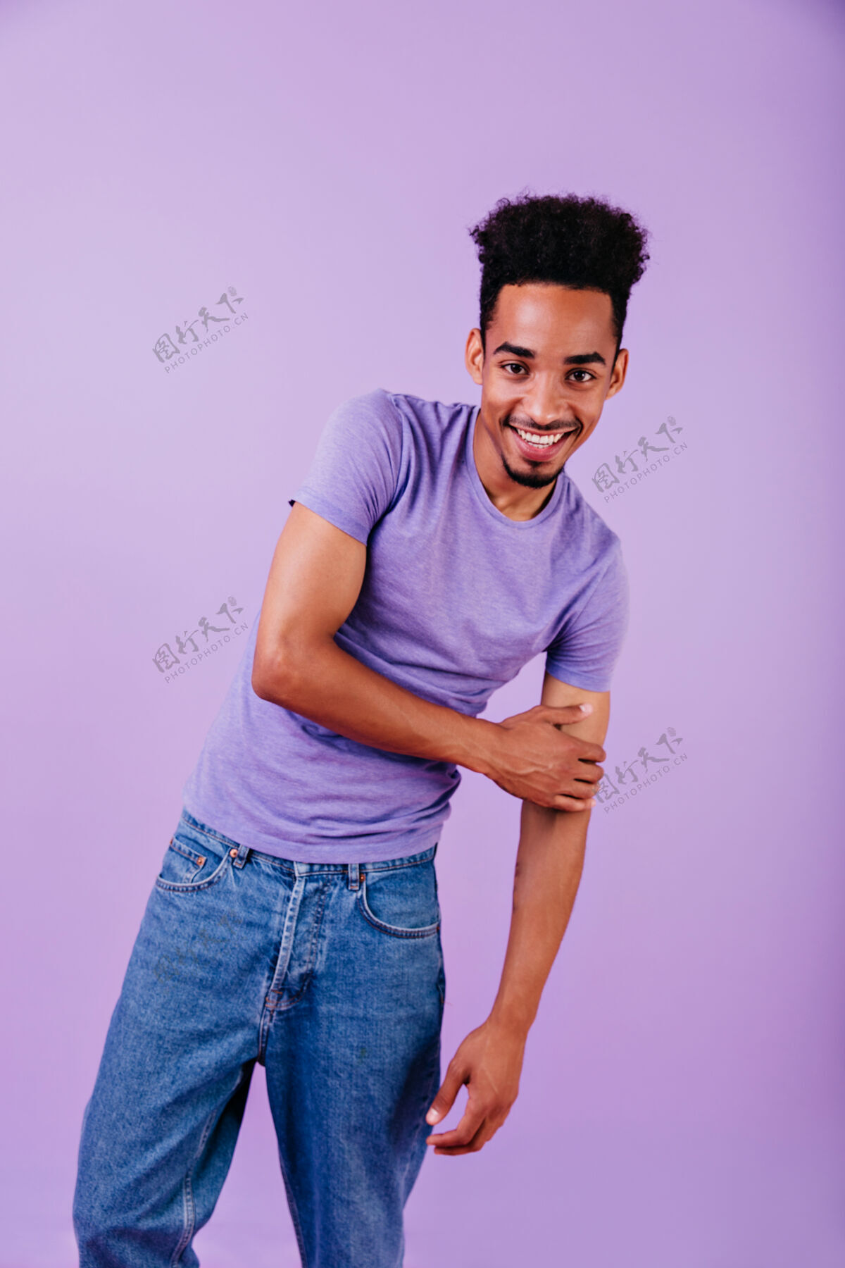 情感一个穿着牛仔裤的可爱男人在笑一张非洲男模站着剪着时髦发型的室内照片紫色移动人