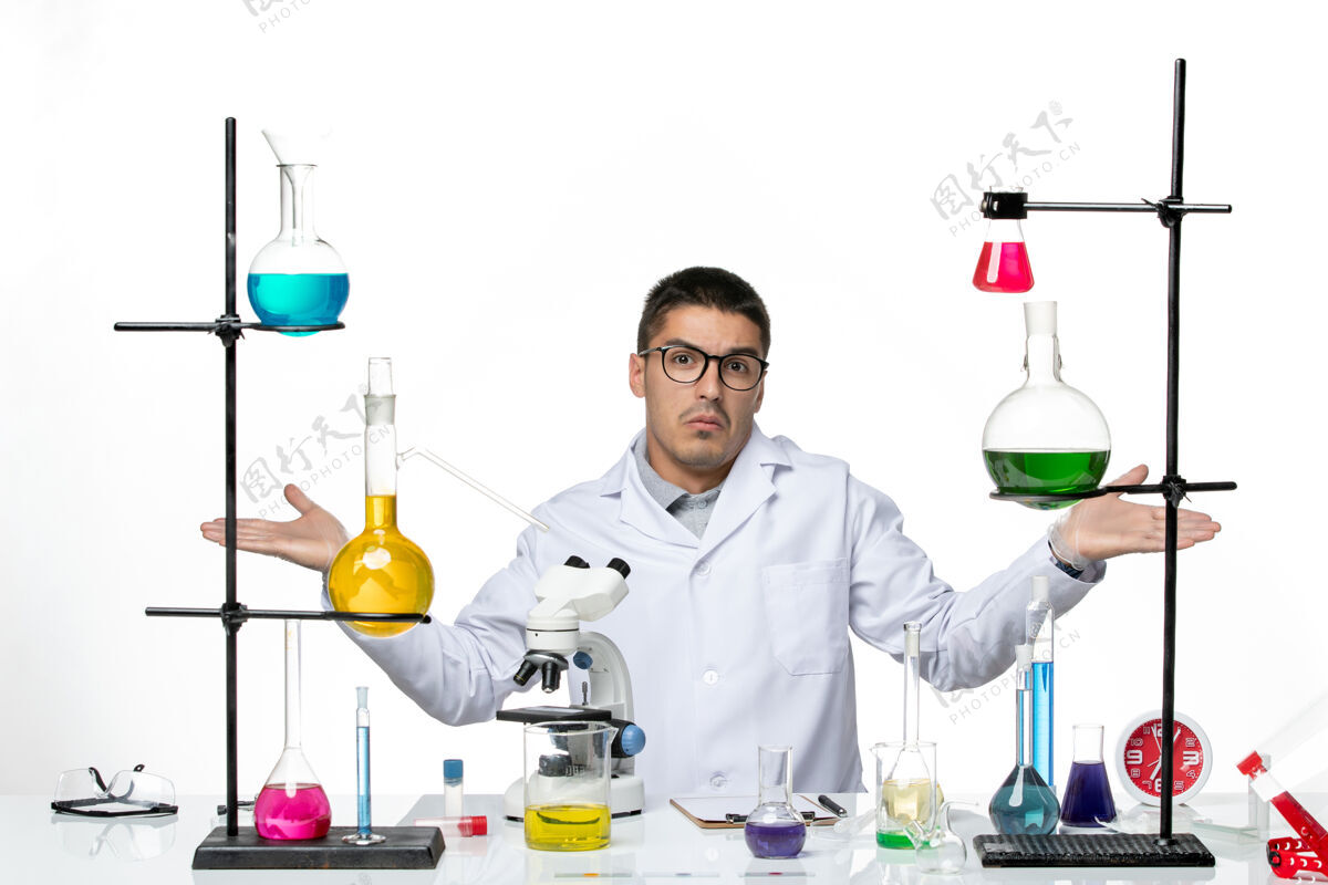 医学前视图穿着白色医疗服的男性化学家坐在白色背景上解决病毒实验室共患疾病科学医院套装科学