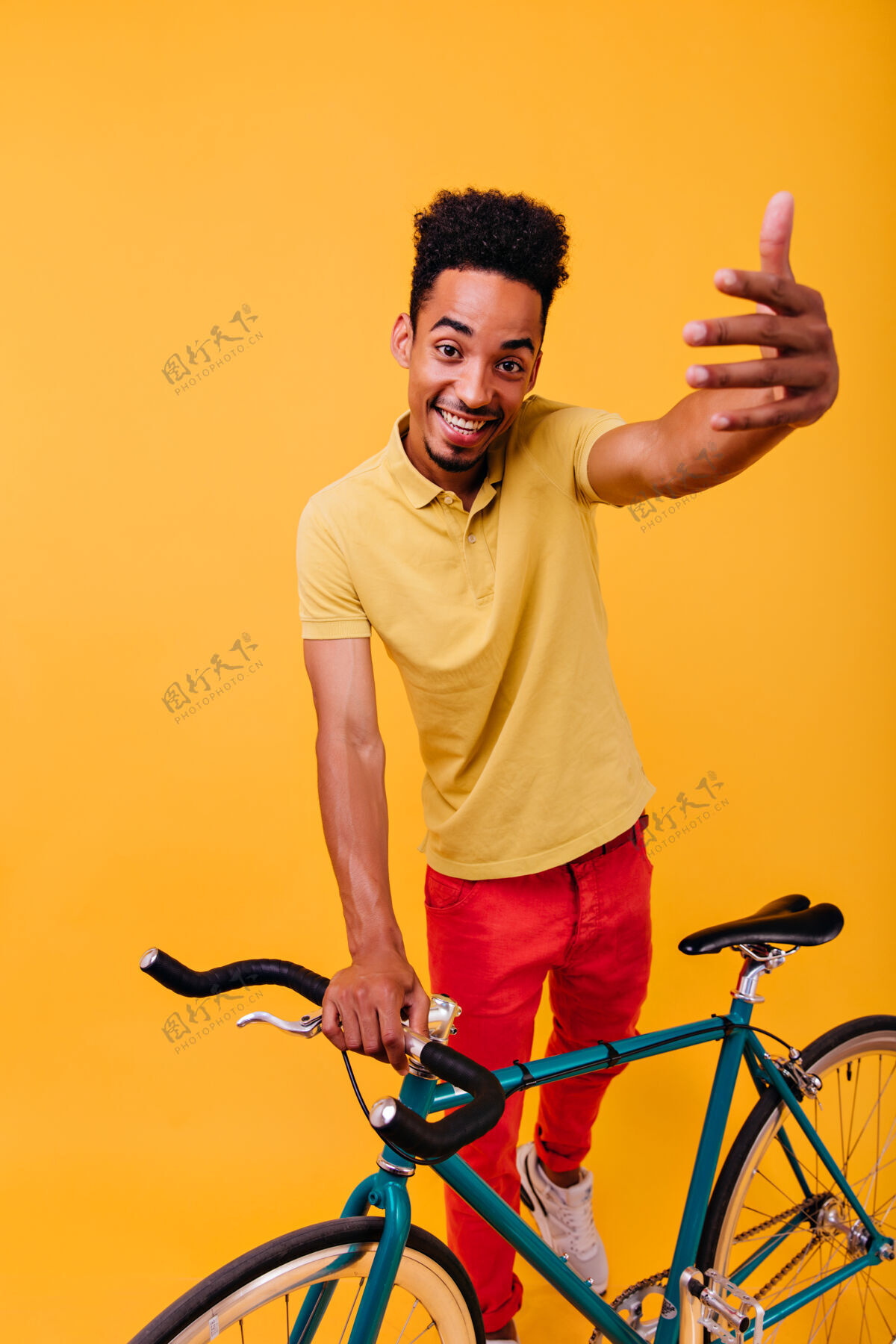 卷发幸福的非洲男孩与绿色自行车合影室内拍摄情绪激动的棕发男模特与自行车站在一起人夏天运动