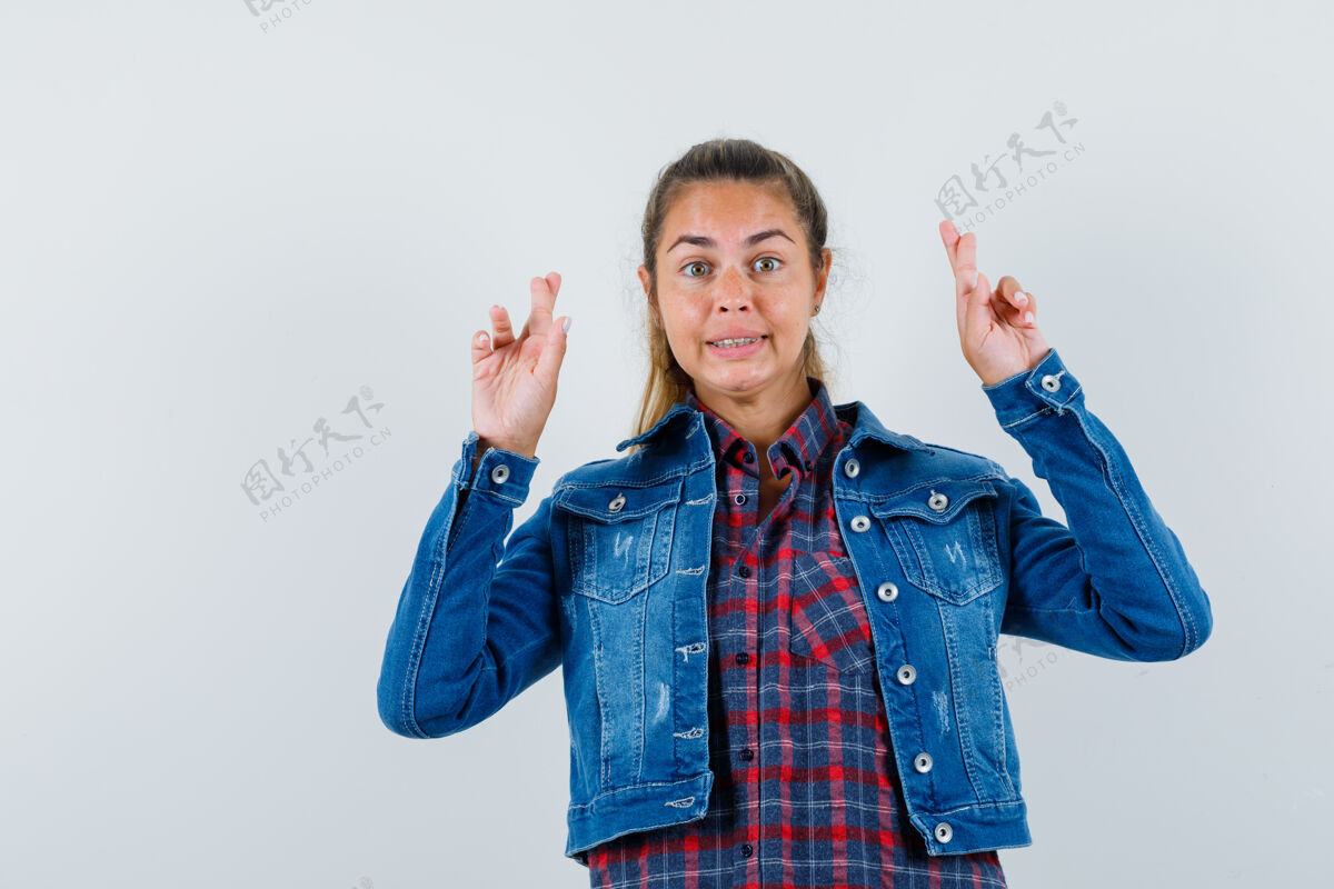 一年轻的女士在衬衫 夹克衫和保持手指交叉看起来高兴 正面视图肖像休闲衬衫