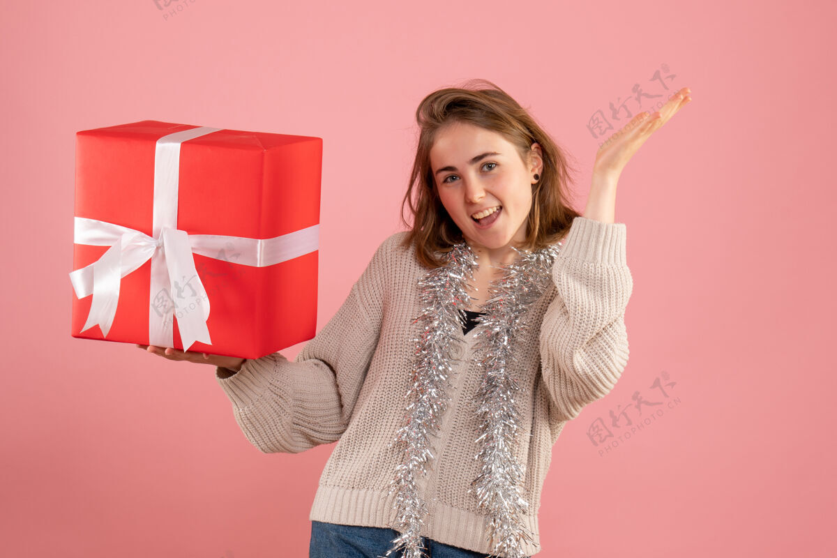粉色正面图年轻女性手持圣诞礼物举行节日时尚