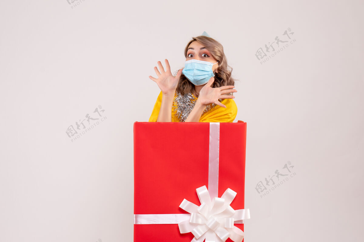 年正面图：戴着面具的红色礼品盒里的年轻女性购物圣诞节里面