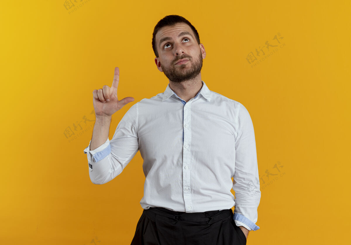 商务男士自信的帅哥看了看 指着橙色的墙上孤立帅气橙色衬衫