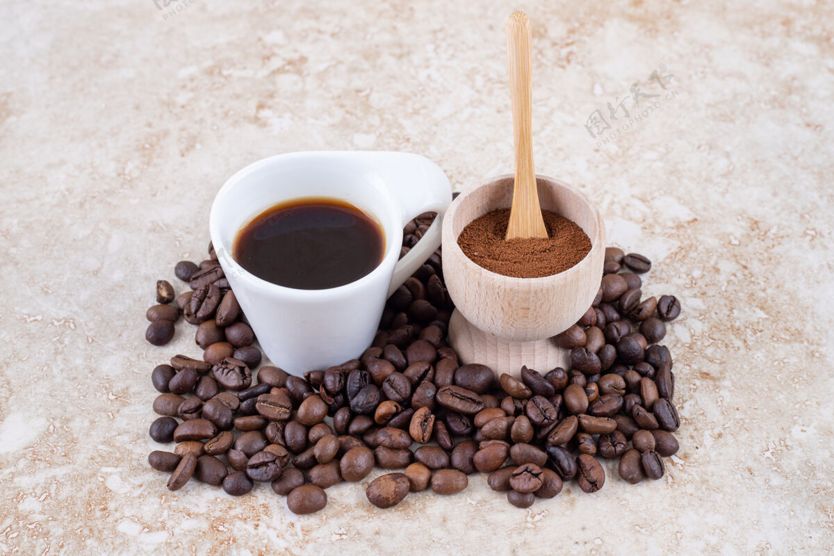 豆一小碗磨碎的咖啡粉和一杯放在一堆咖啡豆上的咖啡地美味碗