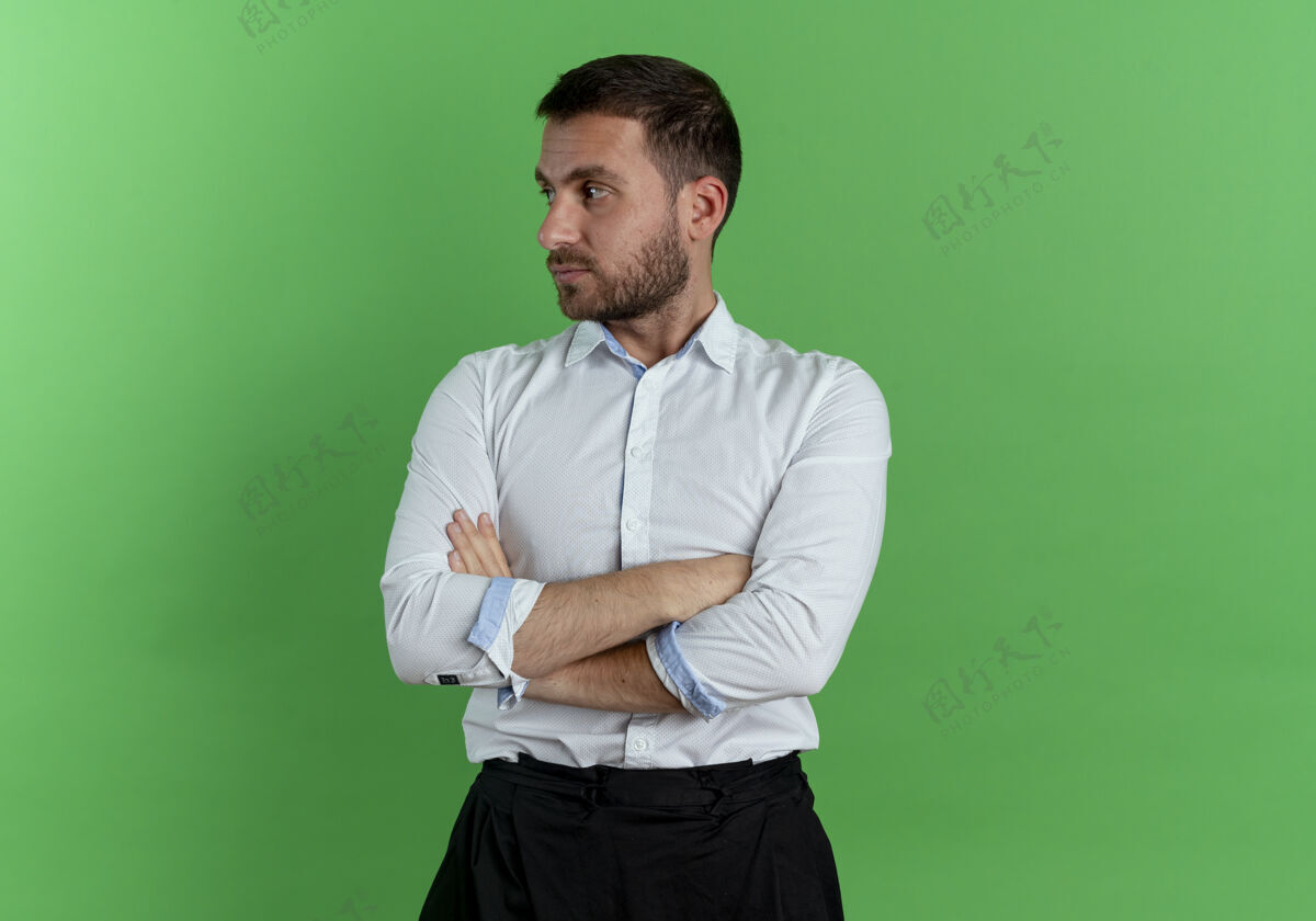 男人自信的帅哥交叉双臂望着绿墙上孤零零的一面绿色自信手臂