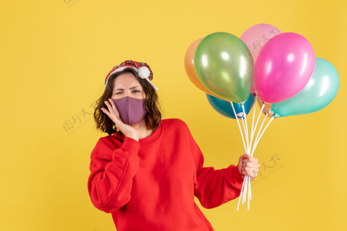 视图正面图年轻女性手持气球 戴着黄色的无菌面具女人聚会庆祝