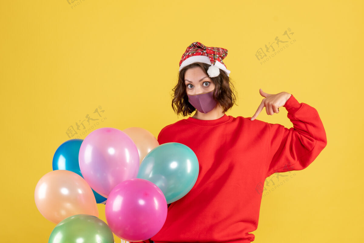 消毒正面图年轻女性拿着气球 戴着黄色的无菌面具面具情感前面