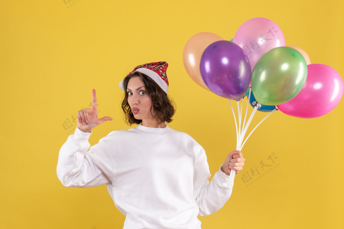女人正面图美丽的女性手持五颜六色的气球站在黄色庆祝黄色气球