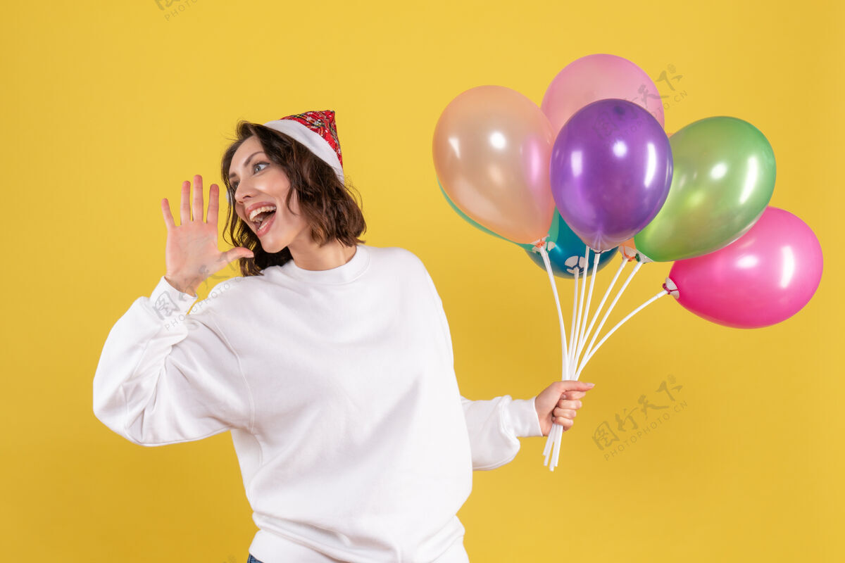 欢乐正面图美丽的女性手持五颜六色的气球站在黄色年份举行气球