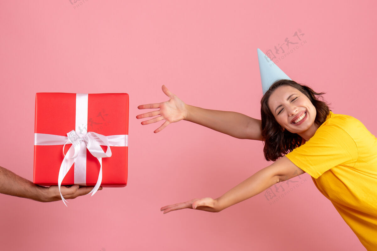 粉色正面图年轻女性在粉色地板上接受来自男性的礼物新年情感圣诞派对女人色颜色礼物正面
