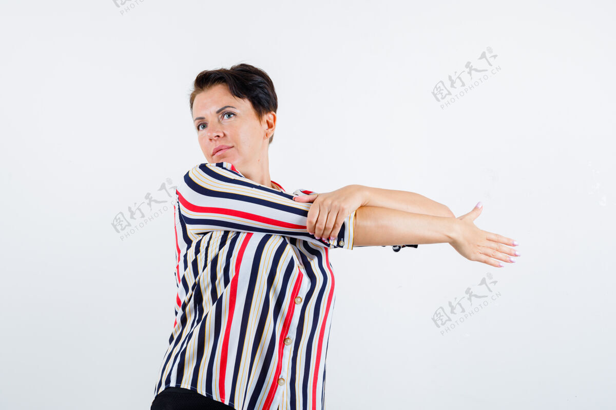手臂成熟的女人伸开双臂 一只手放在手腕上 穿着条纹衬衫 表情严肃 前视健康白发成熟