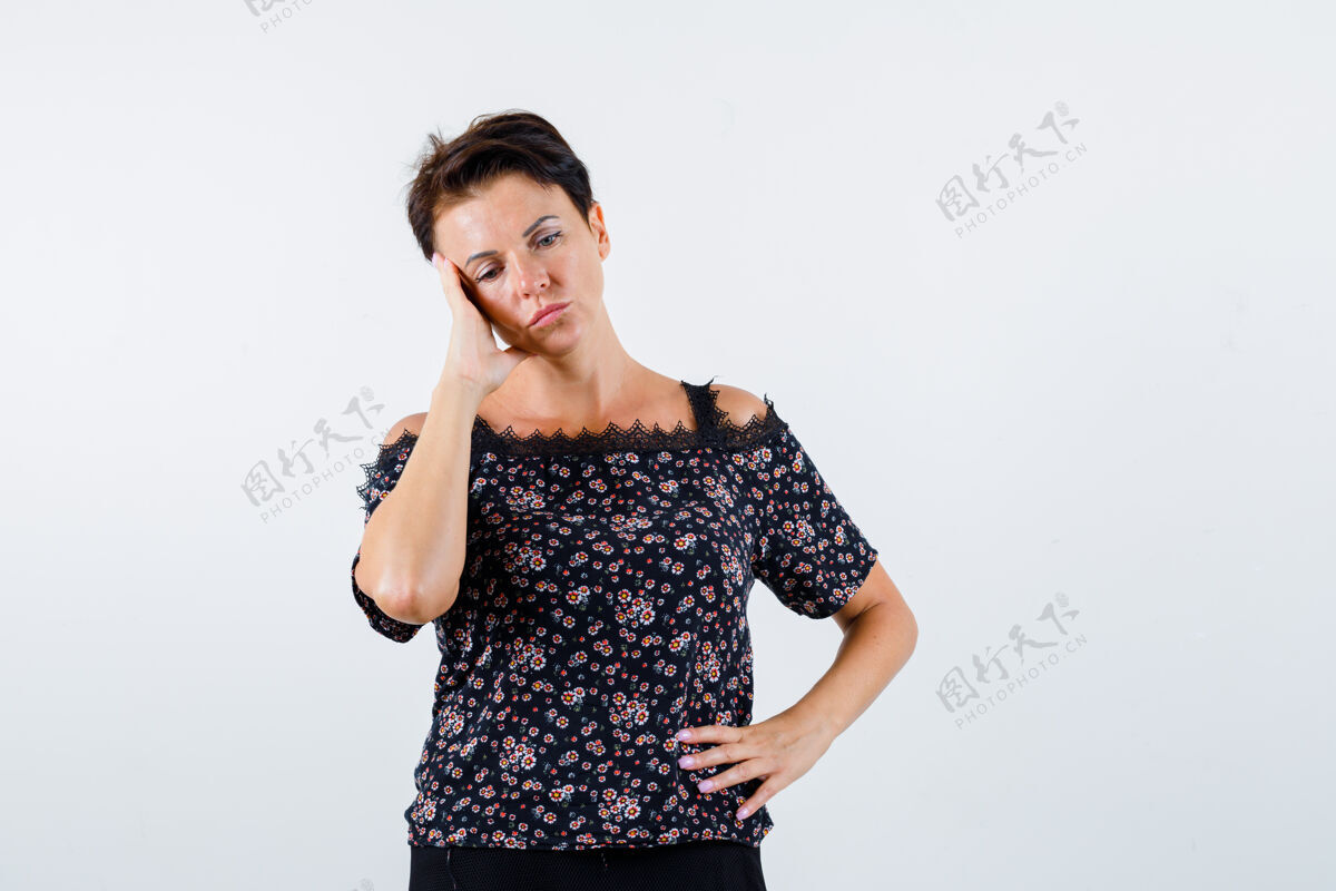 人成熟的女人 手放在腰上 面颊靠在手掌上 穿着花衬衫 黑色裙子 低头看着 沉思着前视图腰围肖像自信