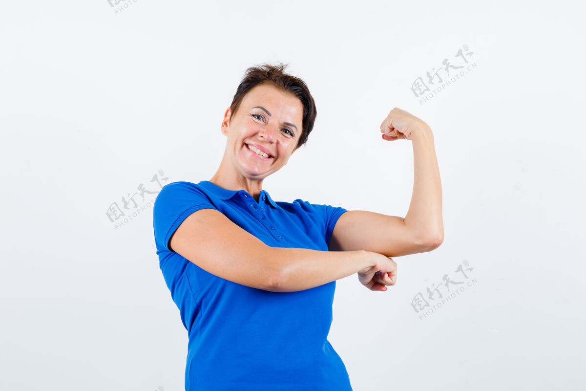 老年穿着蓝色t恤展示手臂肌肉的成熟女性 看起来很高兴正面图皮肤护理健康老年