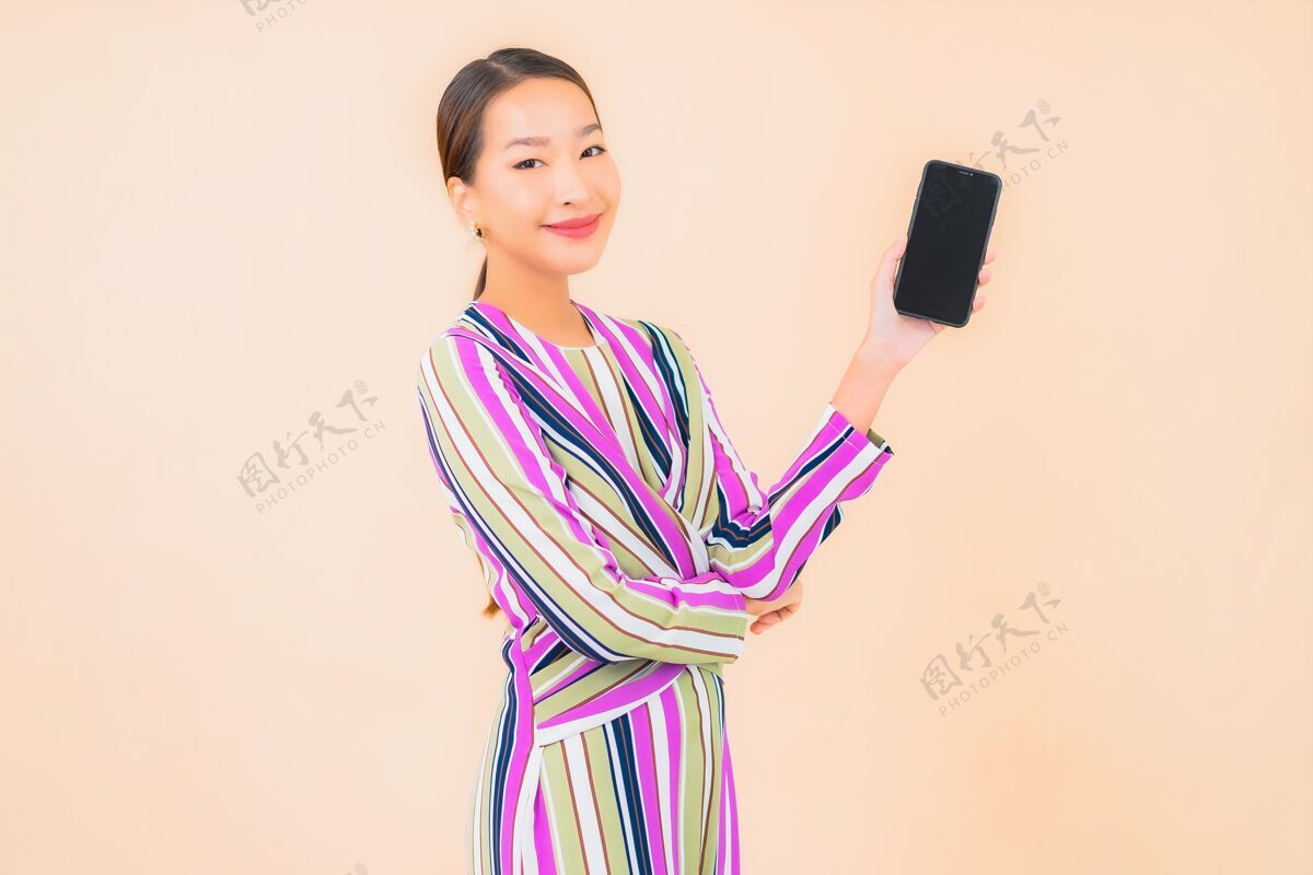 黑发肖像美丽的亚洲年轻女子用智能手机上色电话时尚惊喜
