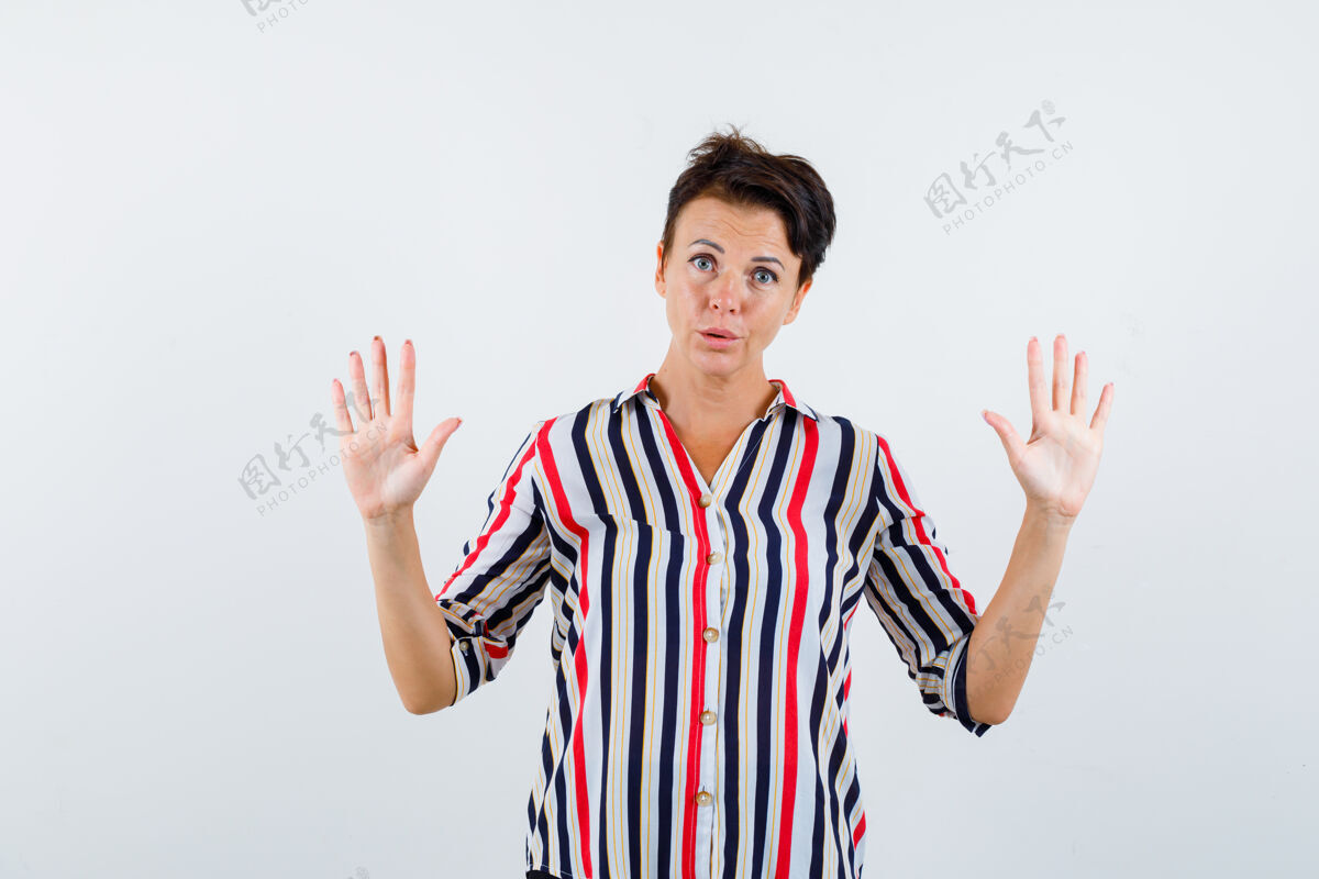 女性成熟的女人 穿着条纹衬衫 露出手掌投降的姿势 脸上露出困惑的表情退休老人