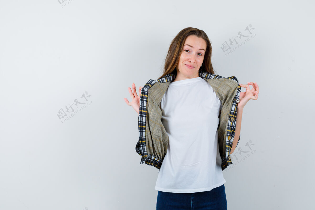 健康穿着t恤 夹克 牛仔裤的年轻女士手拿夹克摆姿势 看起来很可爱 正面照女人魅力牛仔裤