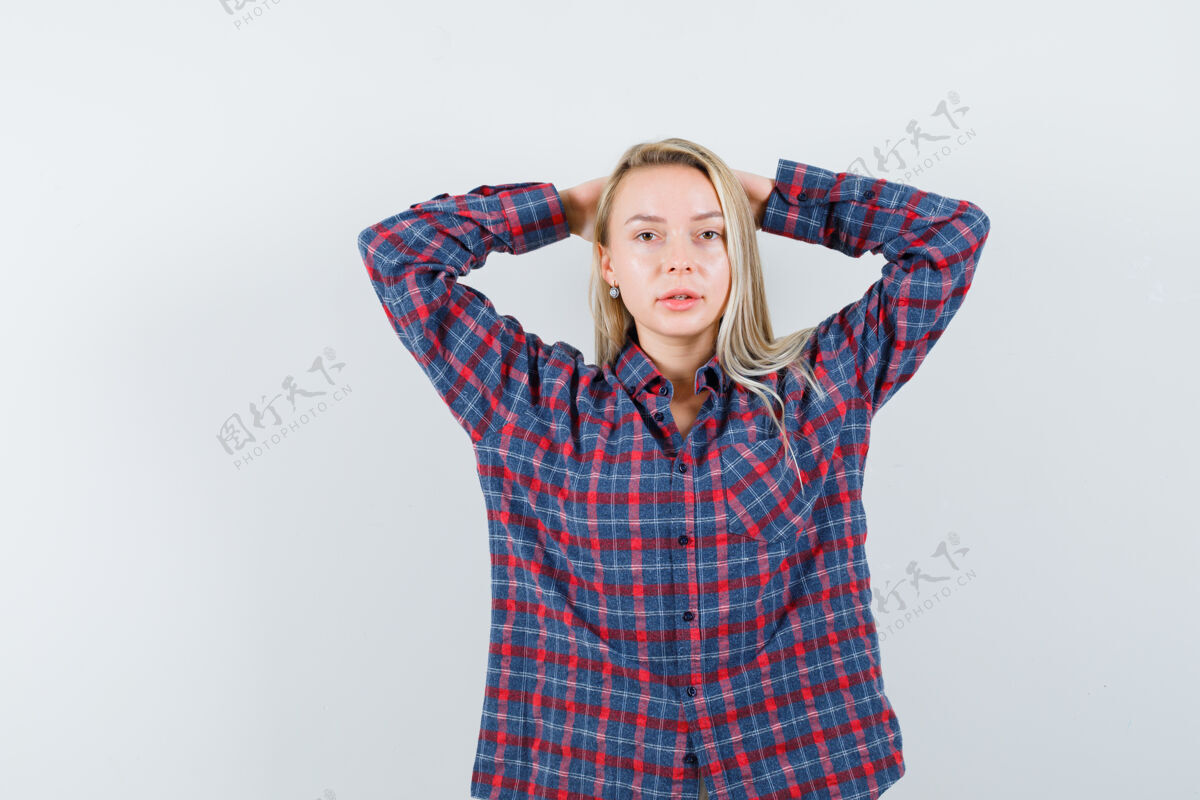 相机金发碧眼的女人 手举在头上 穿着格子衬衫对着镜头摆姿势 看起来很有魅力 正对着镜头头发持有衬衫