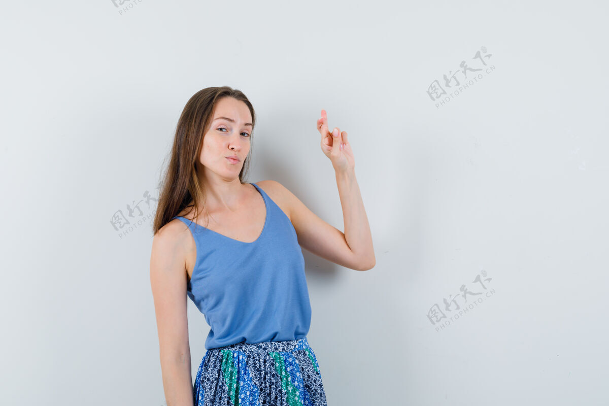 魅力年轻的女士在蓝色上衣 裙子和看起来自信 正面视图交叉手指年轻观众自信