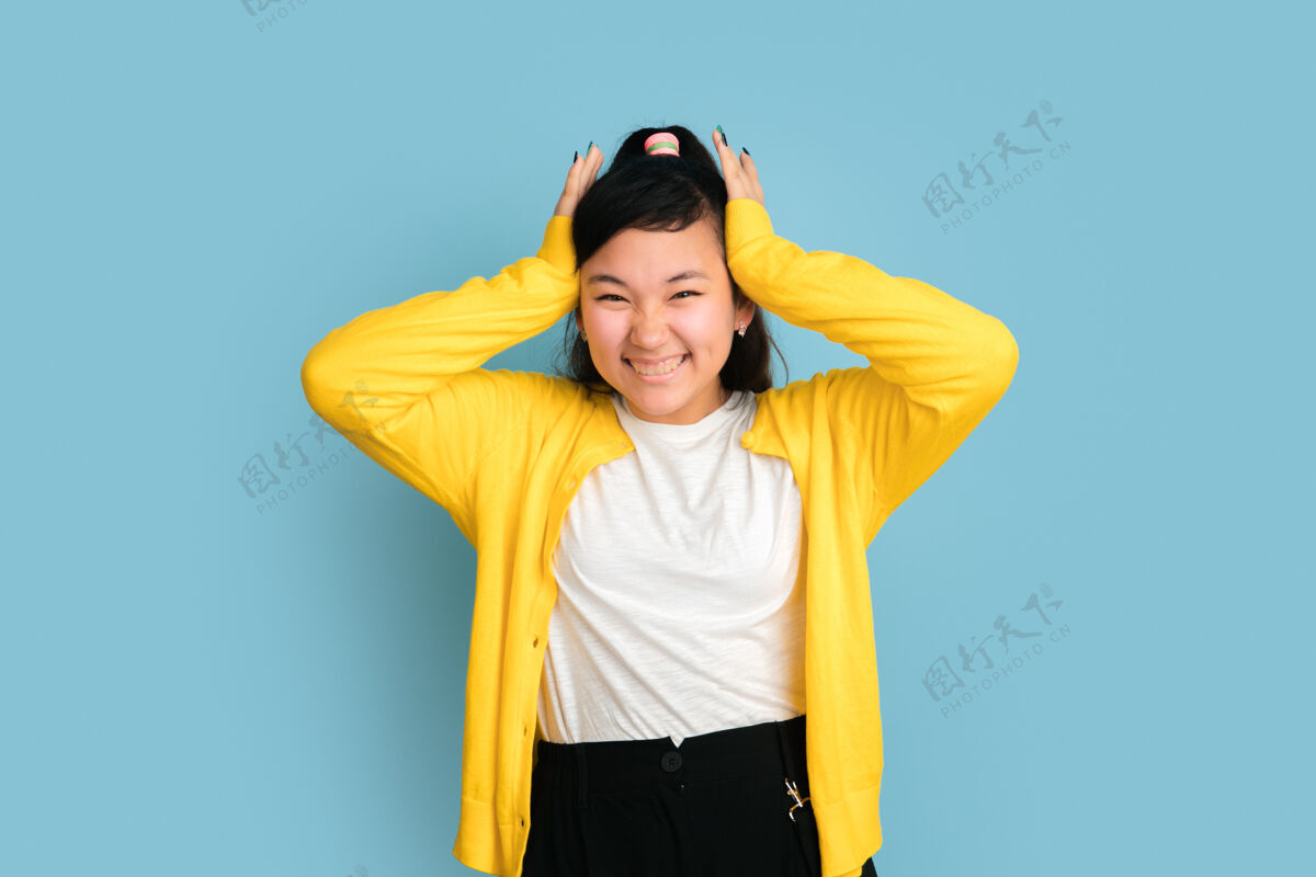 表情在蓝色工作室背景上孤立的亚洲青少年肖像美丽的深褐色长发女性模特人类情感的概念 面部表情 销售 广告笑 双手抱着头面部工作手
