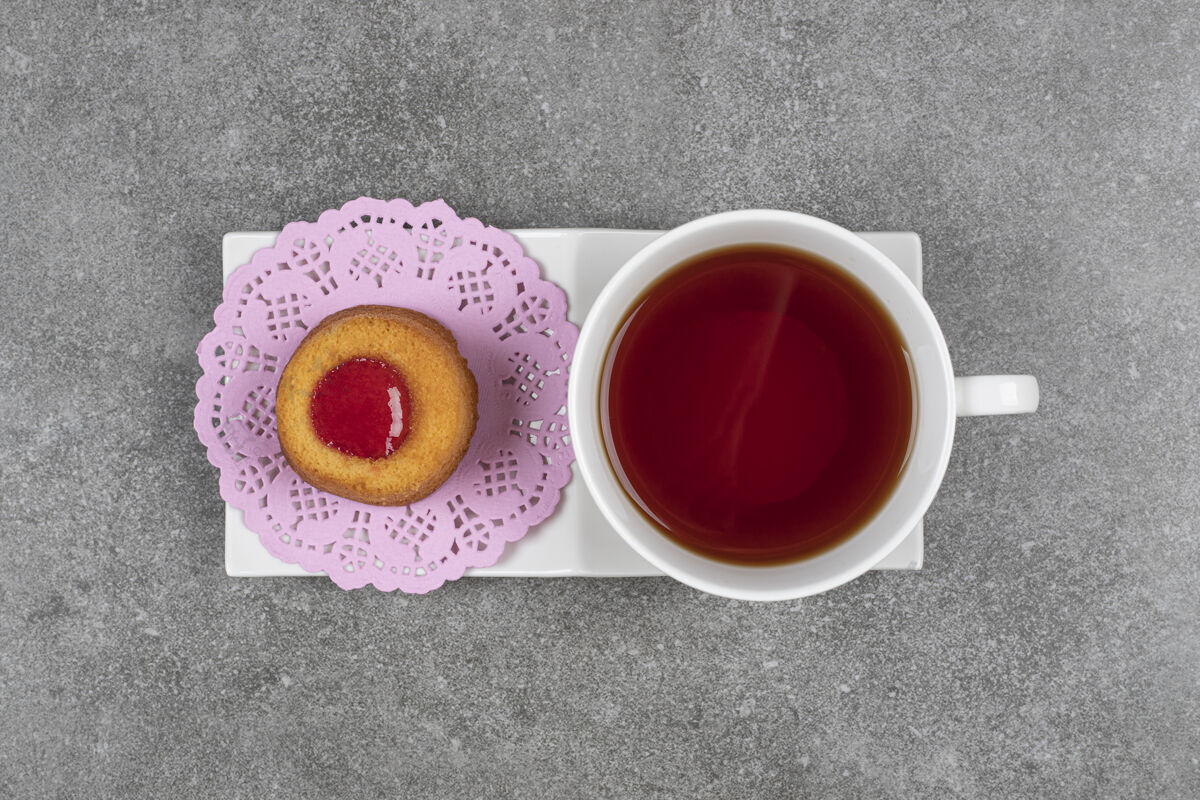 小吃在大理石表面涂上果冻和茶的小蛋糕美味茶碟圆形