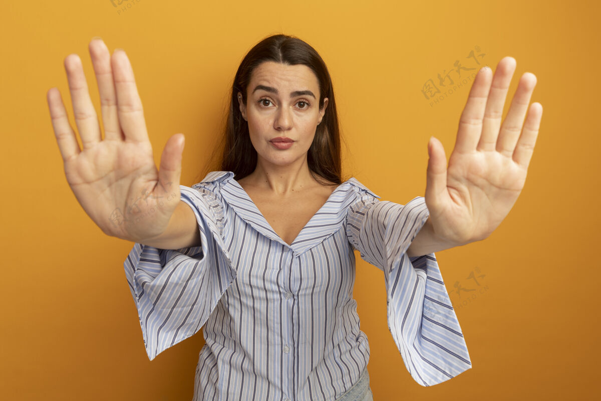 站自信的漂亮女人在橙色的墙上用两只手做手势停止手势女人人感觉
