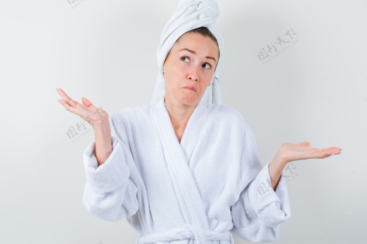 头部穿着白色浴衣 毛巾的年轻女士表现出无助的姿态 看上去很困惑前视图手势时尚魅力