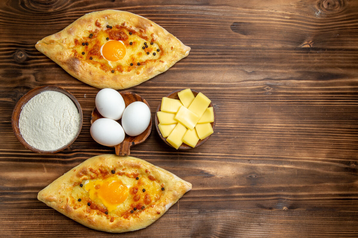 膳食顶视图烤鸡蛋面包从棕色木制桌子上的烤箱新鲜面包面团鸡蛋包早餐面包生的早餐晚餐