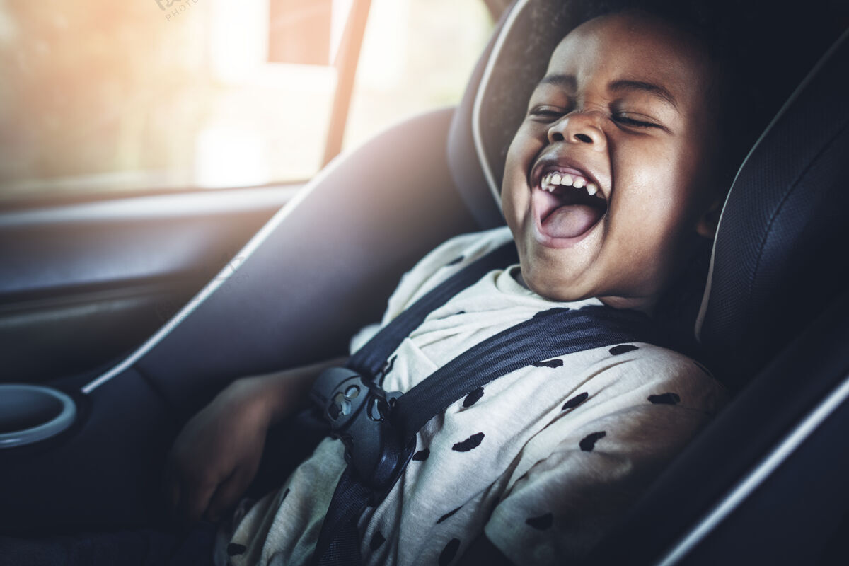 尖叫坐在汽车座椅上的快乐的非洲裔美国孩子车辆孩子乐趣