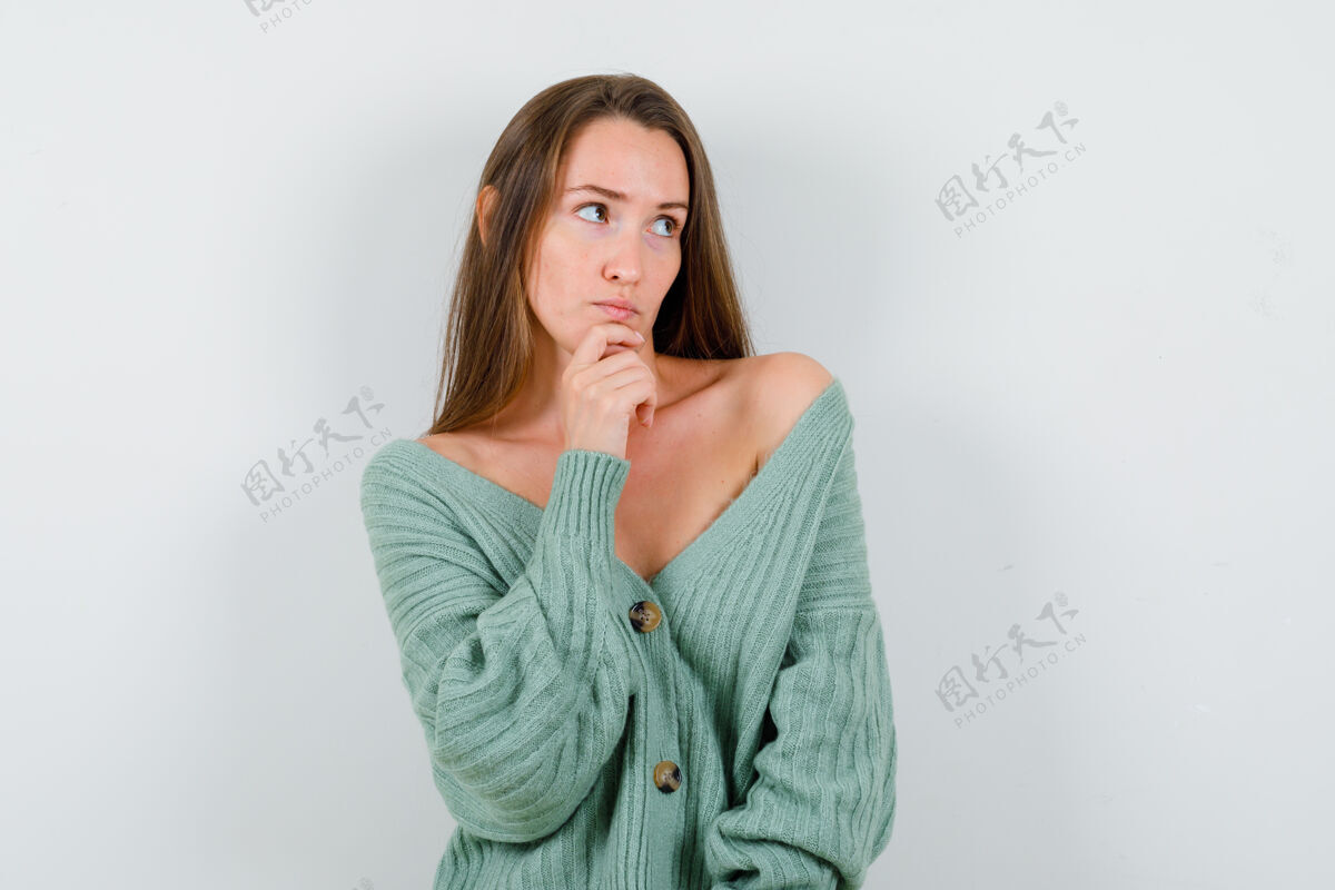 女性穿着羊毛开衫的年轻女士手放在下巴上 神情沉思正面图时尚健康保持