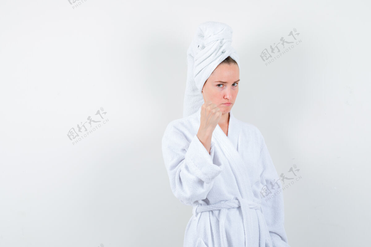 年轻一幅年轻女子握紧拳头穿着白色浴衣 毛巾的肖像 表情凶恶女人头发成人