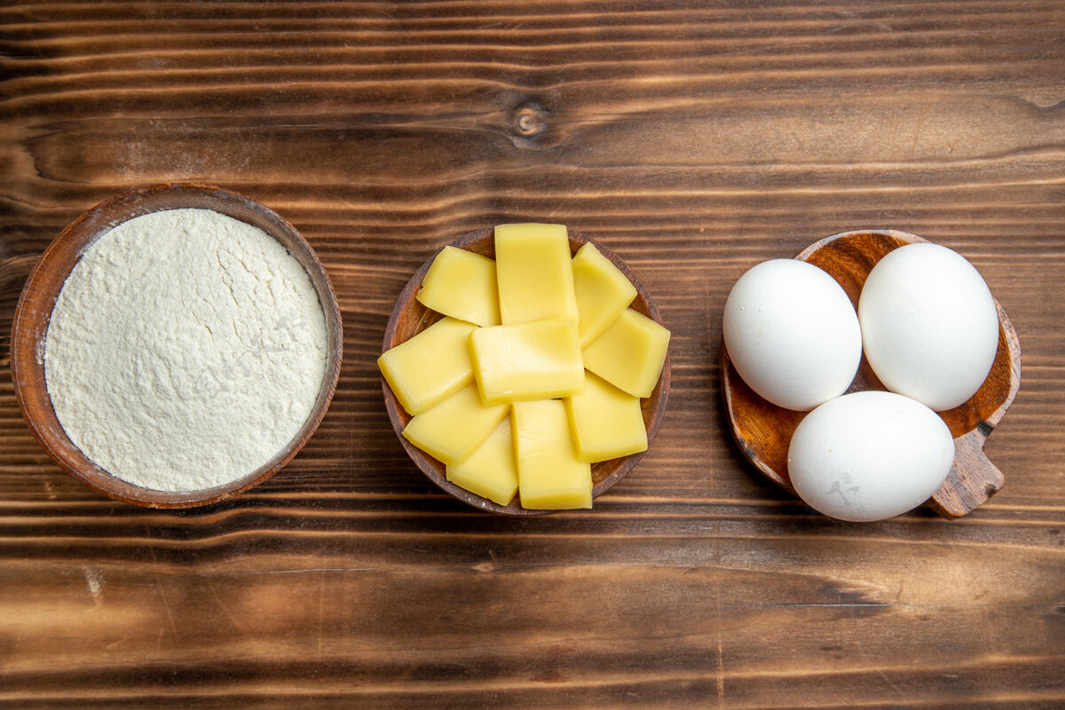鸡蛋俯视整个生鸡蛋与面粉和奶酪在棕色桌上鸡蛋面团面粉粉尘产品产品面团生的