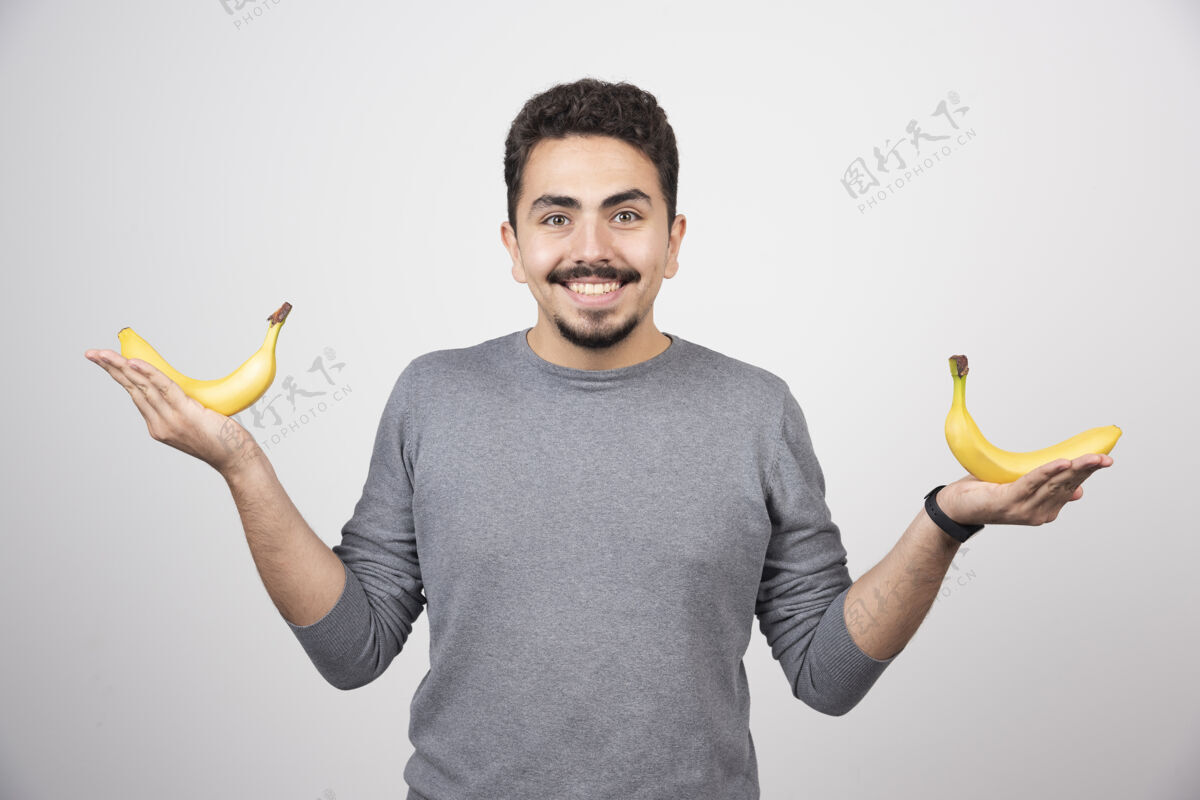 手一个年轻人拿着两个新鲜的香蕉健康食品人指点