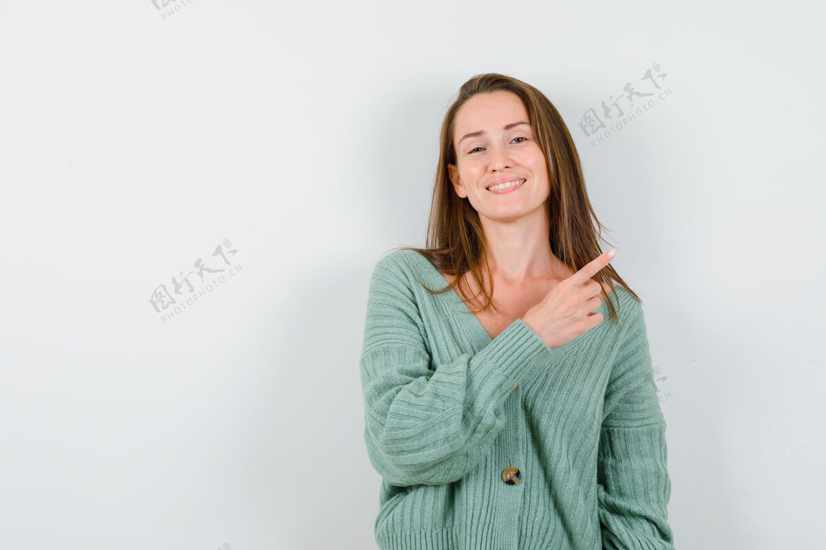女性穿着针织衫的年轻女孩用食指指着右边 看起来很开心 正面照好模型卷发