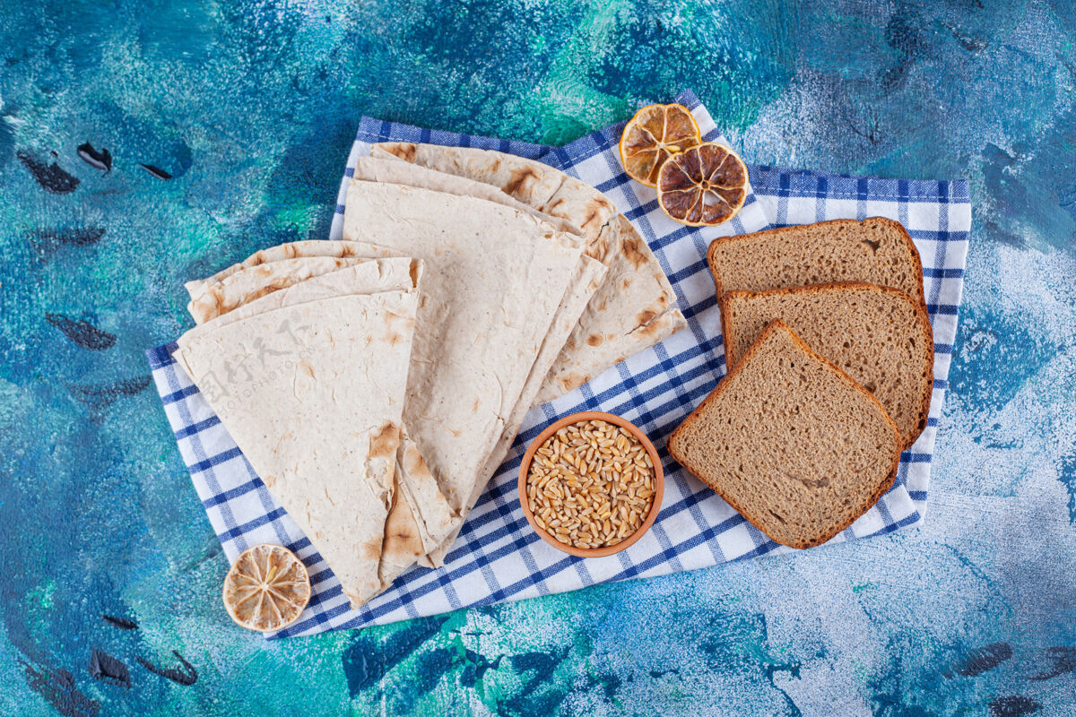 大麦各种新鲜芳香的面包 蓝色表面有一碗大麦碗黑麦面包