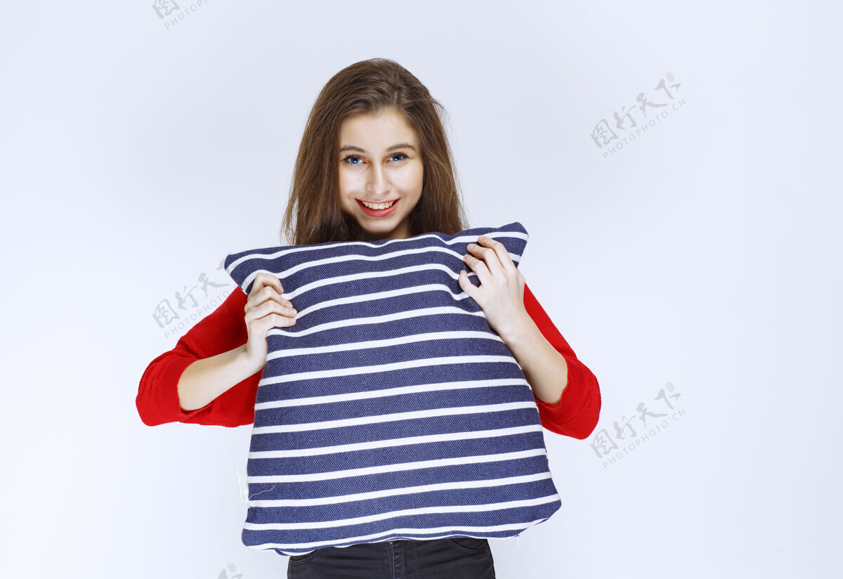 产品年轻女子抱着蓝色条纹的枕头 心情很好姿势快乐女性