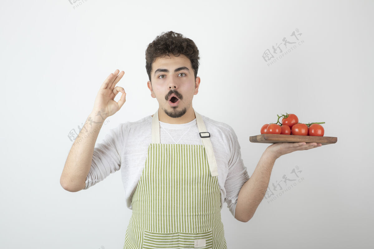 Ok标志兴奋的年轻人手里拿着一堆新鲜的西红柿 做着好的手势工人人蔬菜