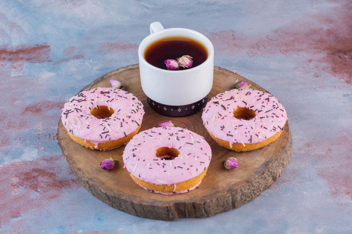 美味美味的甜甜圈加粉色糖衣和一杯红茶糖果霜戒指