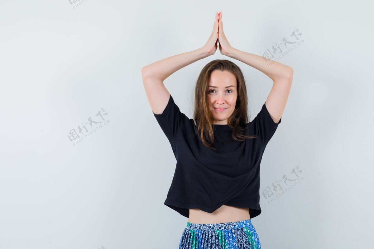 Namaste身穿黑色t恤和蓝色短裙的年轻女子在头上摆出了一副快乐的姿势魅力亚洲漂亮