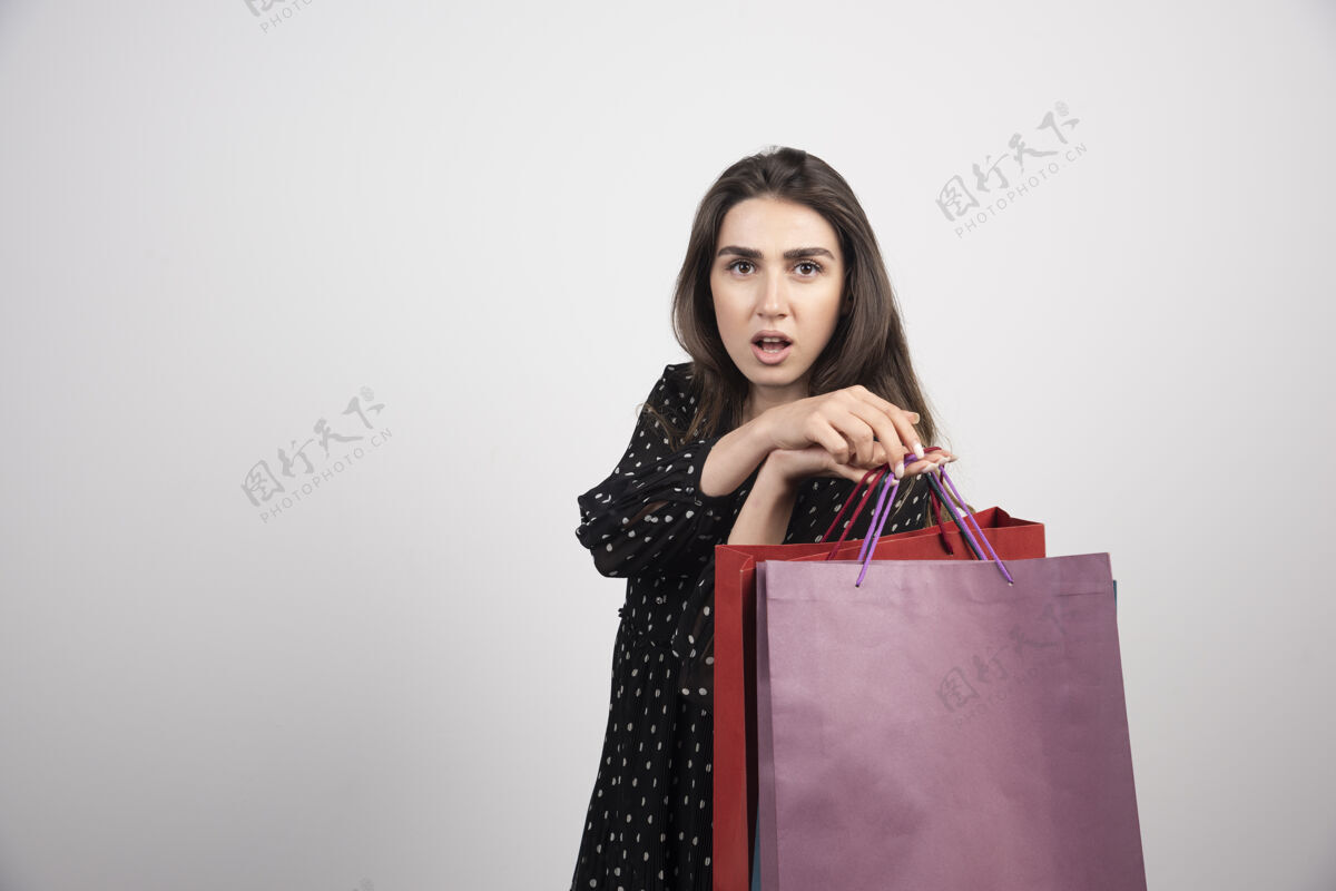 年轻年轻的女模特背着很多购物袋购物者女士购买
