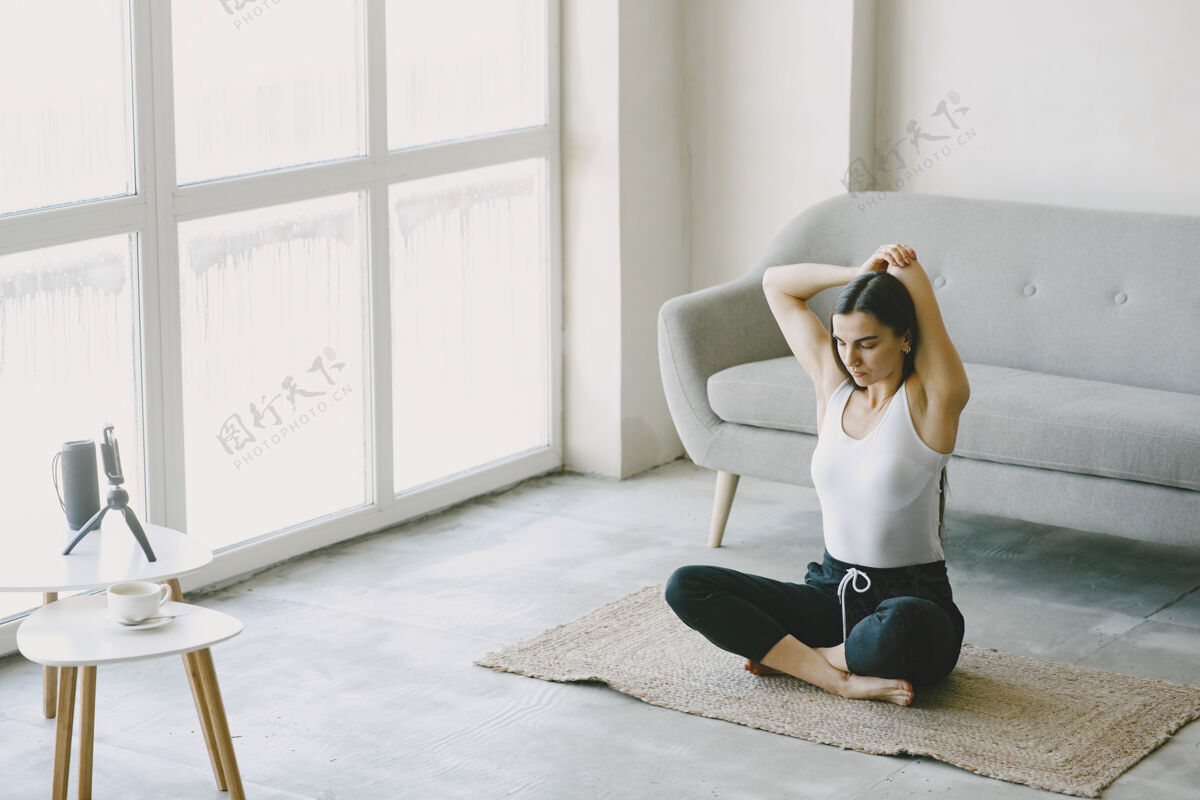 活跃女孩看着电话瑜伽士在揉女人在家里穿着运动服一护理锻炼