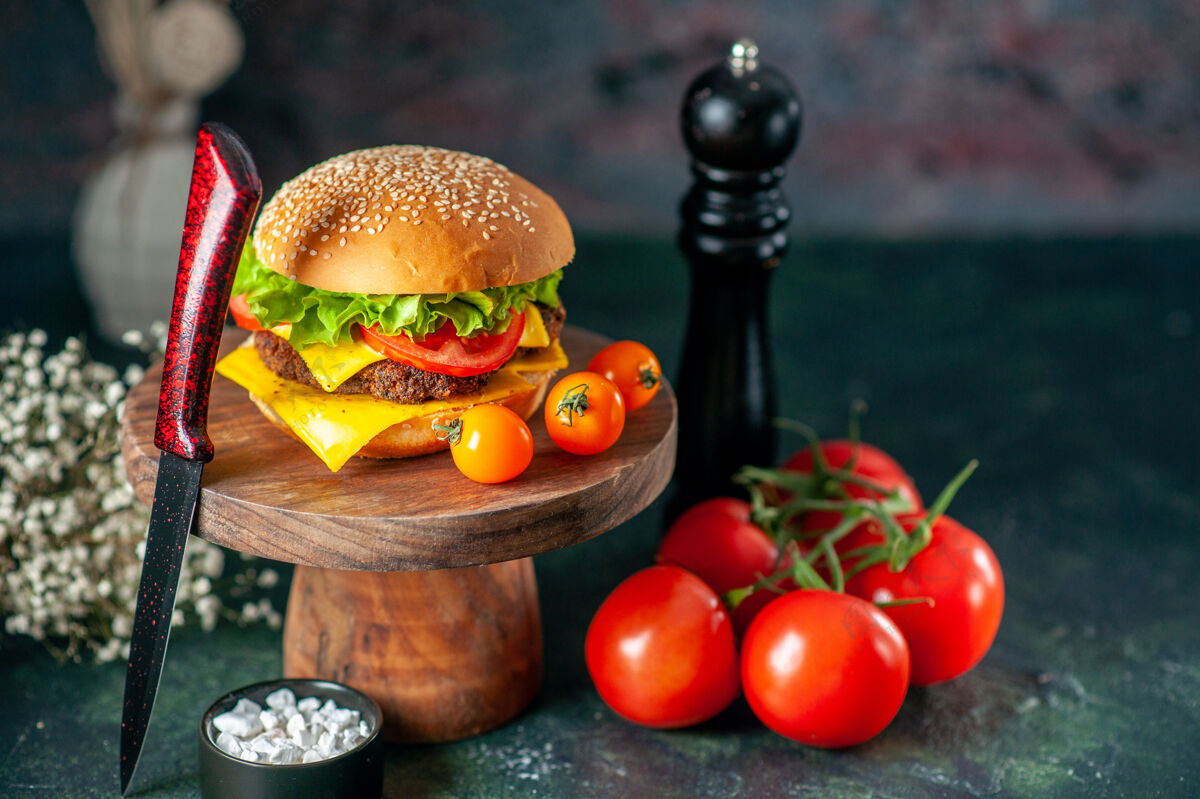 黑前视图美味的肉汉堡包与刀西红柿和胡椒摇瓶在黑暗的背景快餐刀西红柿