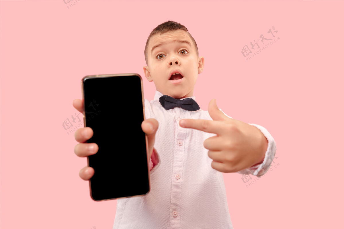 手机室内肖像的迷人的年轻男孩拿着空白的智能手机显示持有手机