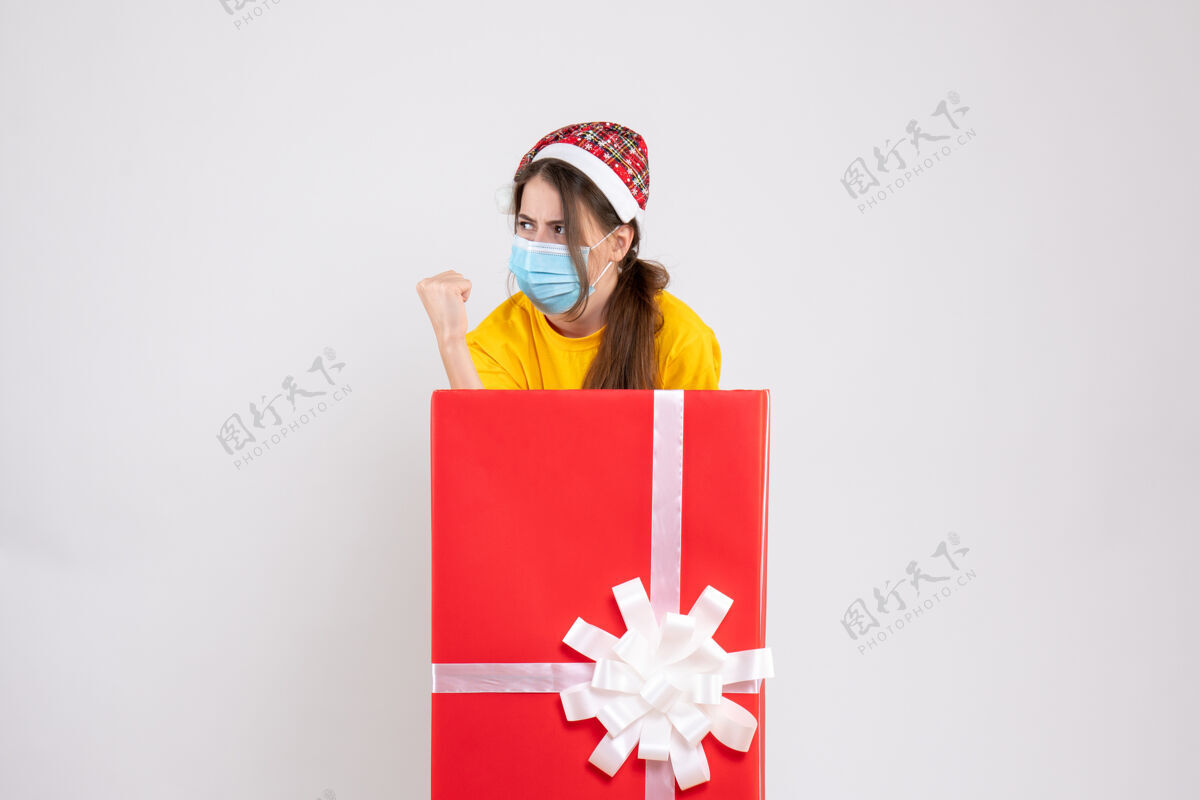 坚定的女孩前视图确定与圣诞礼物背后站着圣诞帽女孩立场庆祝购物者