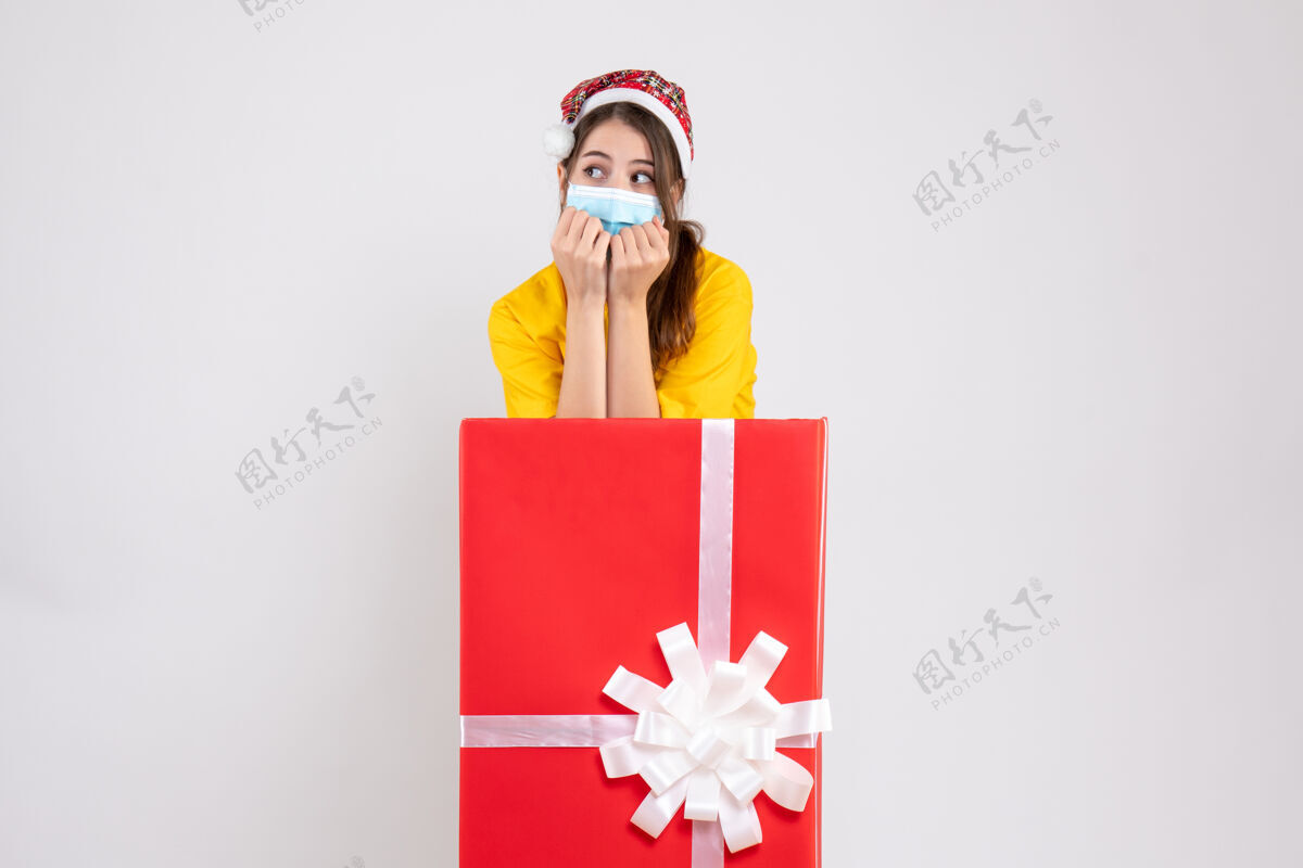 礼物前视图可爱的圣诞女孩与圣诞老人帽子站在背后大圣诞礼物站空间圣诞