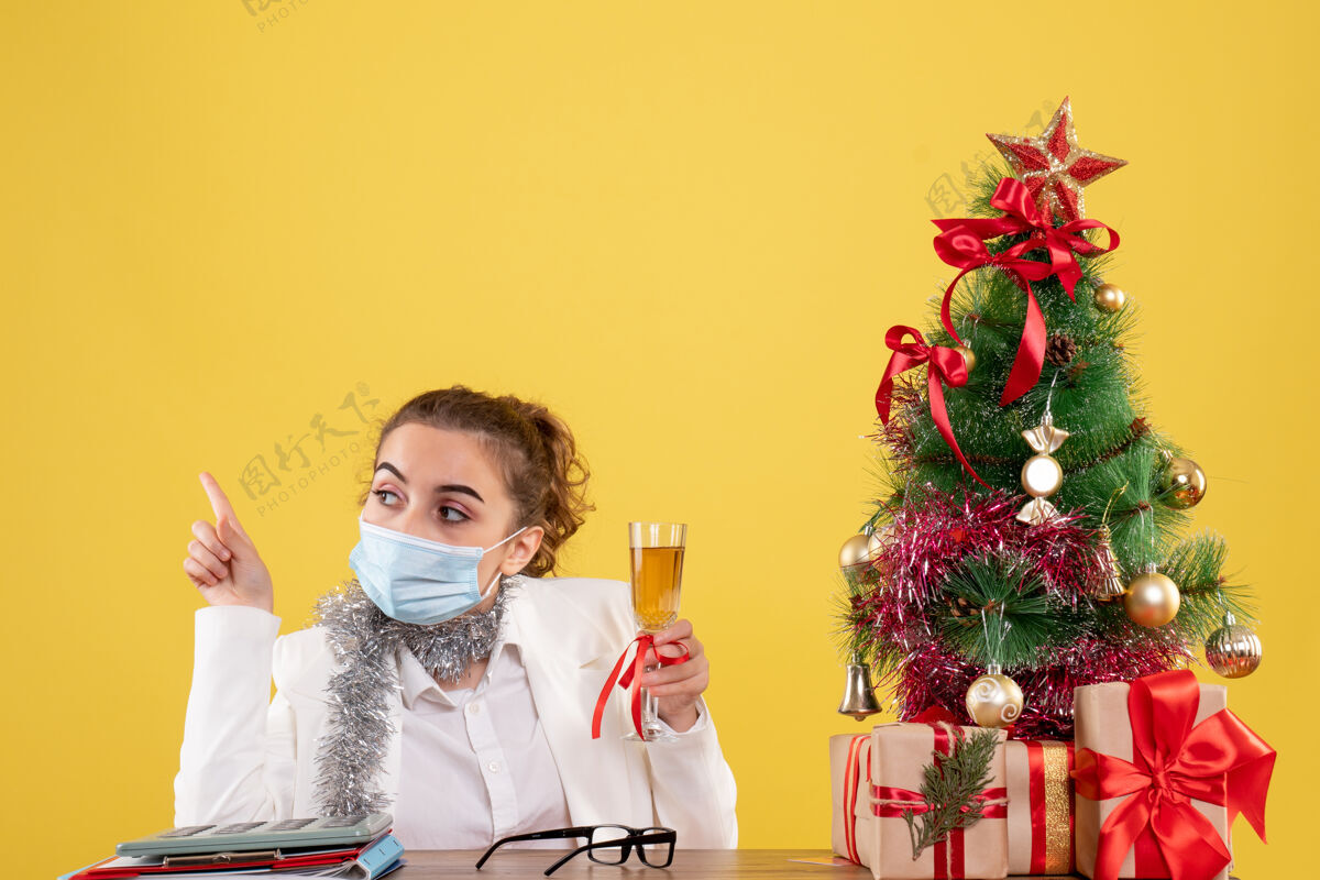 脸正面图戴面具的女医生用香槟庆祝圣诞节病毒圣诞节香槟