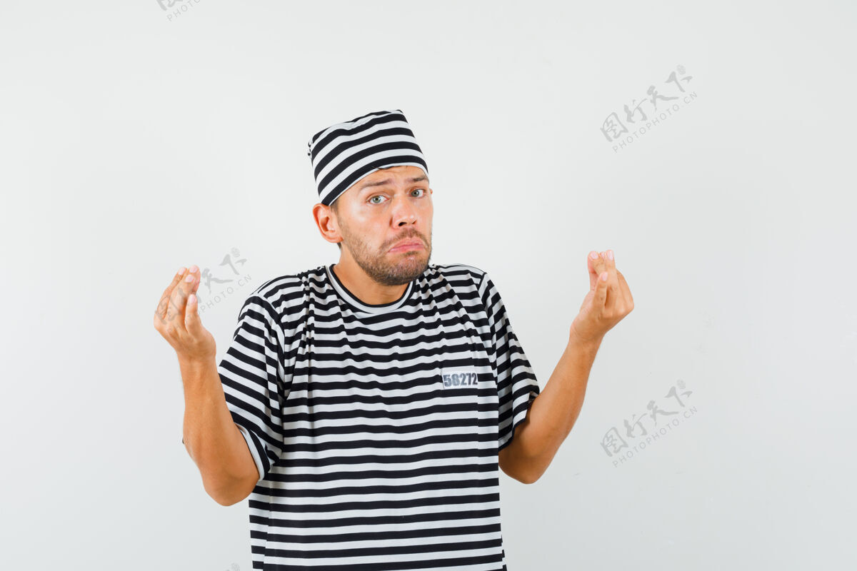 休闲一个年轻人戴着条纹t恤帽子 做着意大利手势 对愚蠢的问题感到不高兴衬衫条纹问题