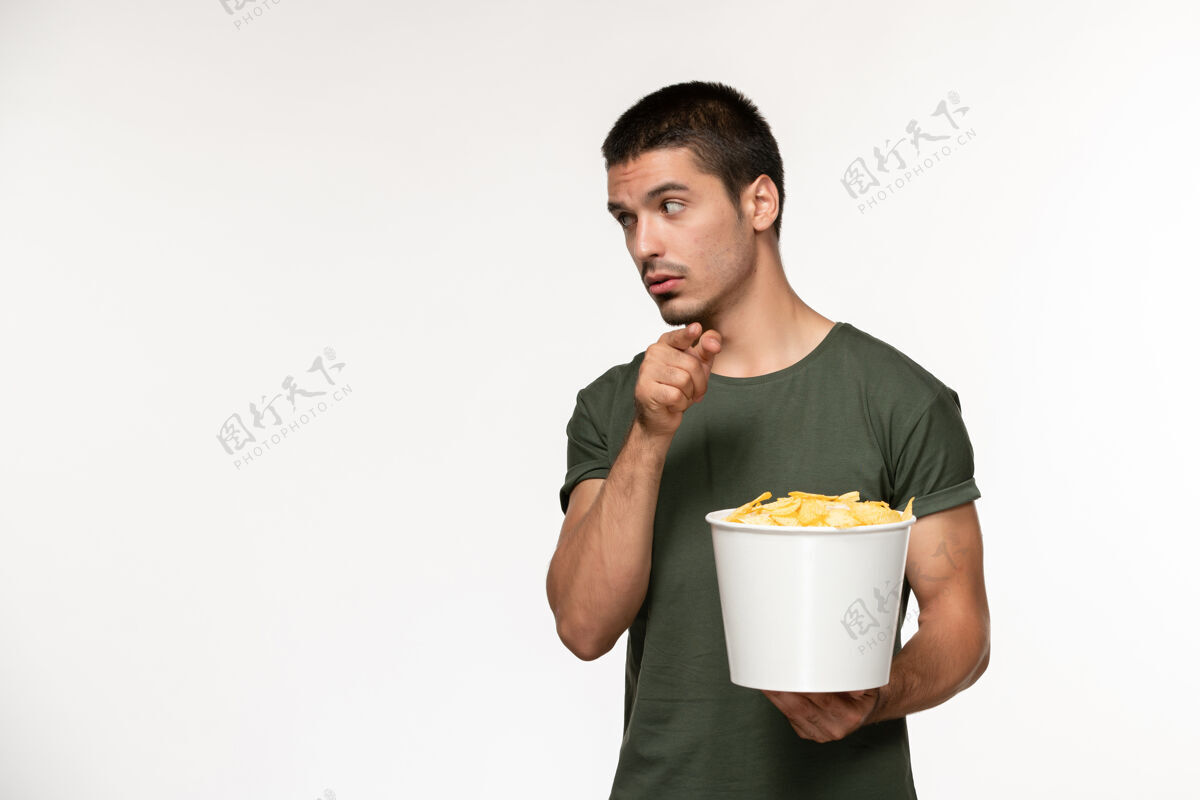 年轻男性正面图身穿绿色t恤的年轻男性手持篮子 白色墙上有cips电影人男性孤独电影电影院电影视图微笑