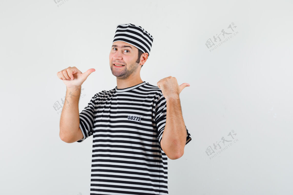 时尚年轻的男性穿着t恤 戴着帽子 用拇指指着后面 看起来很自信 正对着前方人男人年轻