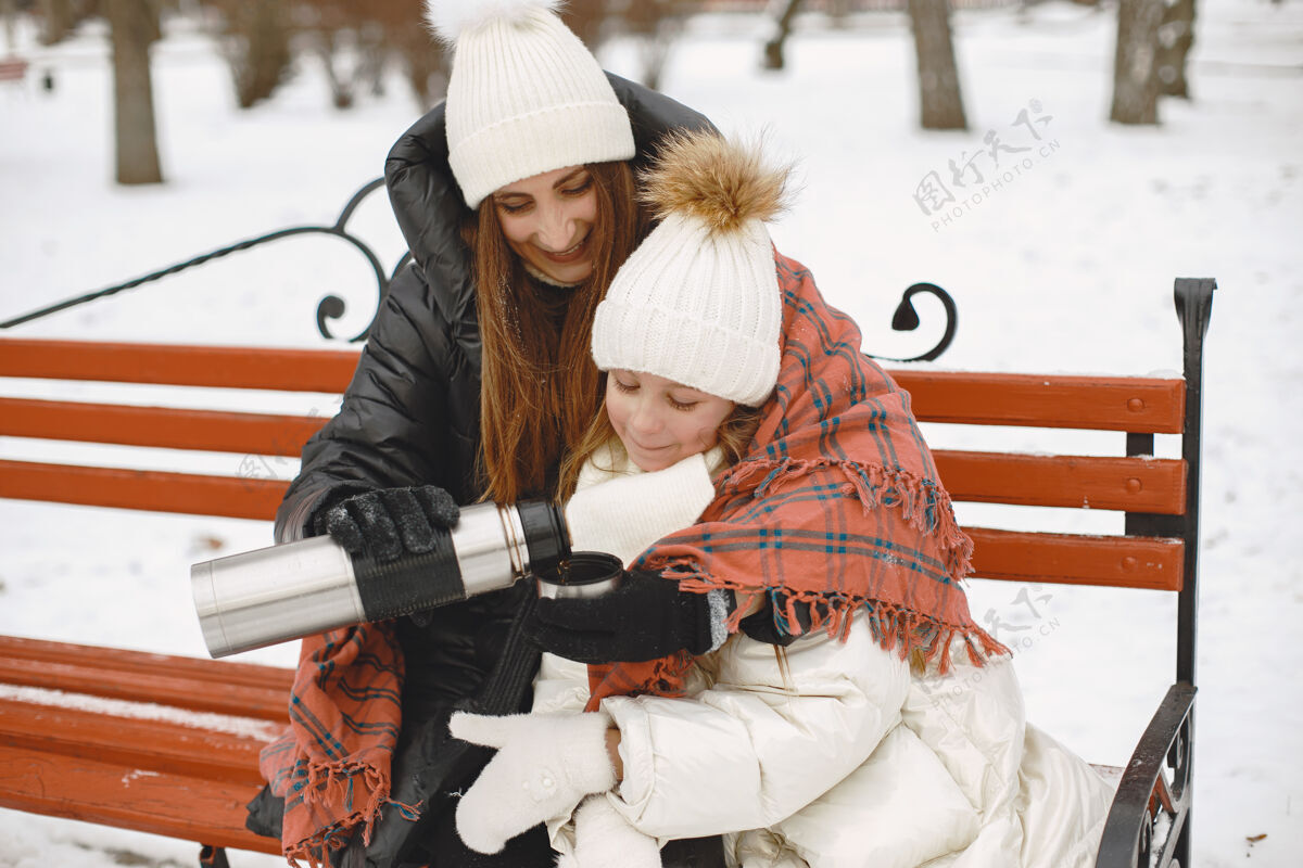 冬天坐在长凳上的女人和小女孩寒冷女性毛衣