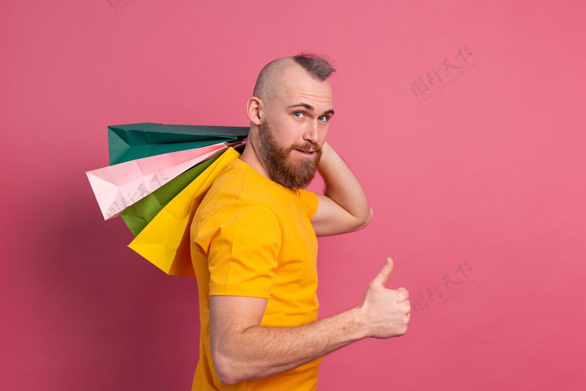 成人快乐的胡须积极的男人休闲装扮与五颜六色的购物袋工作室粉红色的背景购物狂男人商场